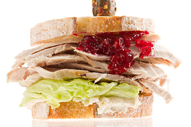 Turkey Sandwich Macro "A close up of a turkey sandwich consisting of pugliese bread, fresh green lettuce, mayonnaise, turkey, homemade red cranberry relish and a peppered olive. Isolated on white." relish green food isolated stock pictures, royalty-free photos & images