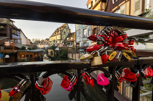 Locks o love on iron fence of a bridge over Lauch river overlooking half timbered houses at Colmar,Alsace,France