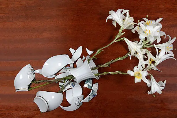 Close up of the broken bowl with lilies on a table.