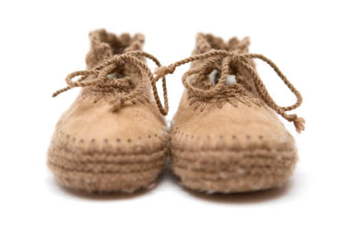 Tiny newborn baby shoes on paper background with copy space. Baby clothes concept. Top view, flat lay