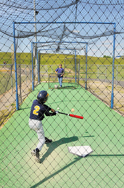 istock Little League Baseball Player in Batting Cage with Coach Pitching 184927494