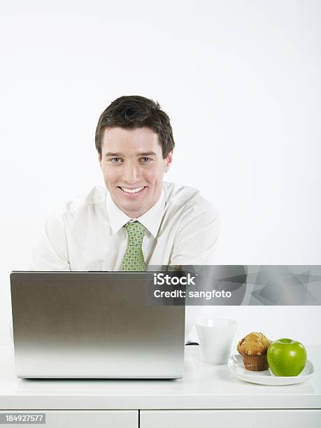 Hombre De Negocios Trabajando En Portátil Sonriendo Con Refrigerios Sanos Foto de stock y más banco de imágenes de 20 a 29 años