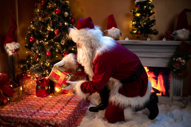 istock Santa claus putting presents under the tree 1849289850