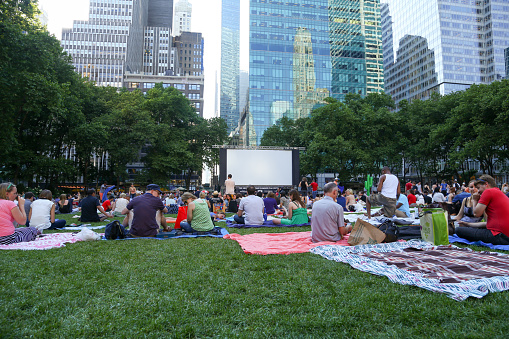 NEW YORK, USA - JUNE 17, 2013 : New yorkers and tourists enjoying HBO Bryant Park Summer Film Festival. People enjoying the summer evening on the Bryant Park lawn, surrounded by the tall buildings of Midtown Manhattan. The film festival brings classic films to a big screen during the summer months.