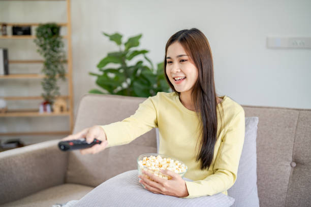 istock Asian woman Watching smart TV and using remote controller Hand holding television audio remote control at home with the remote control television 1849300594