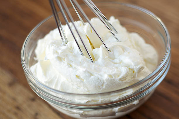 Natural light photo of whipped cream and whisk in glass bowl on rustic wood tablePlease view more rustic food images here: