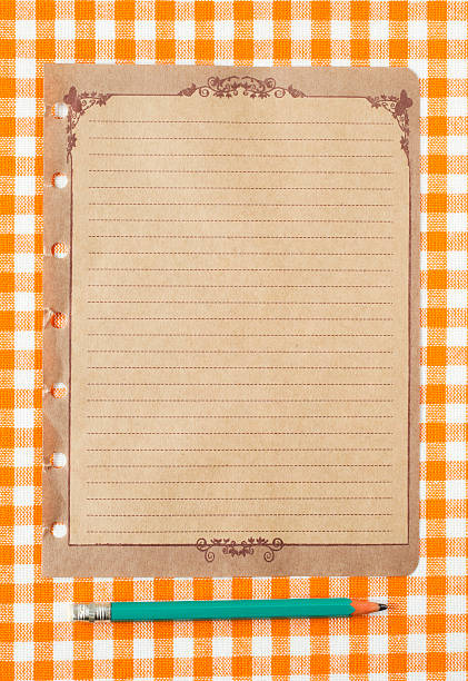 istock Pencil and old paper on orange tableclot 184930129