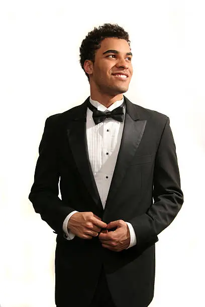 Young minority guy in a tuxedo isolated on white