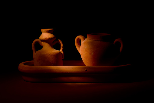 A pair of small terracotta amphorae on dark background