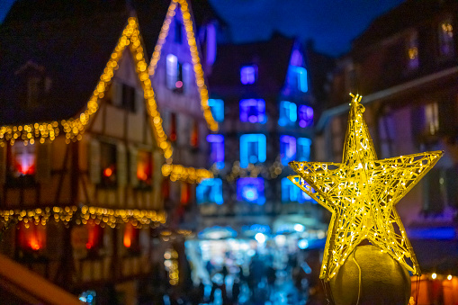 Illuminated star shape decor with traditional old half-timbered houses in the historic town of Colmar,decorated and lighted during the Christmas season,France