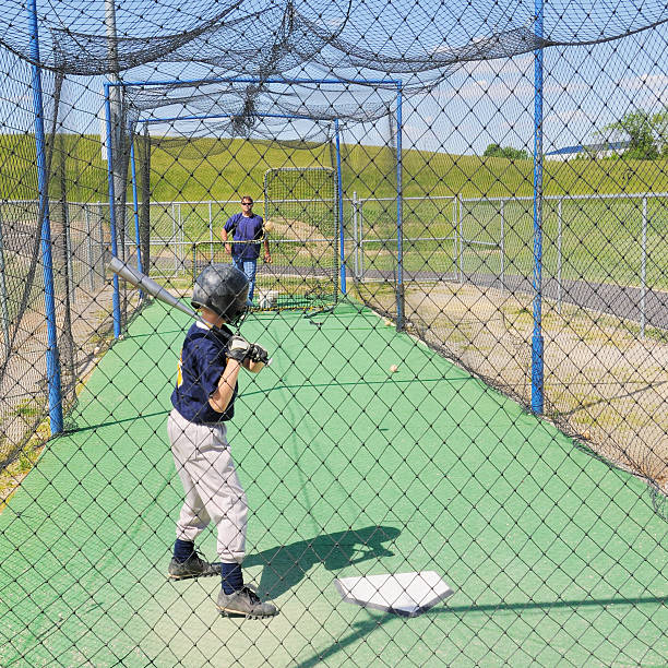 istock Little League baseball player in batting cage with coach 184932026