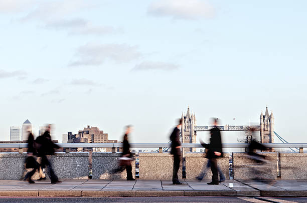 London Commuters Blurred commuters walking along London Bridge with landmarks in the background london docklands stock pictures, royalty-free photos & images