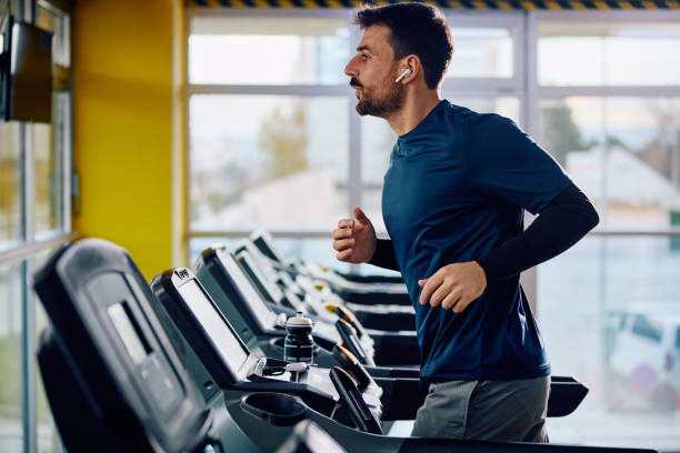 istock Sportsman with earbuds jogging on running track while working out in a gym. 1849329053