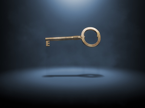 Old fashioned bronze key levitating over dark backgorund. Solution concept.