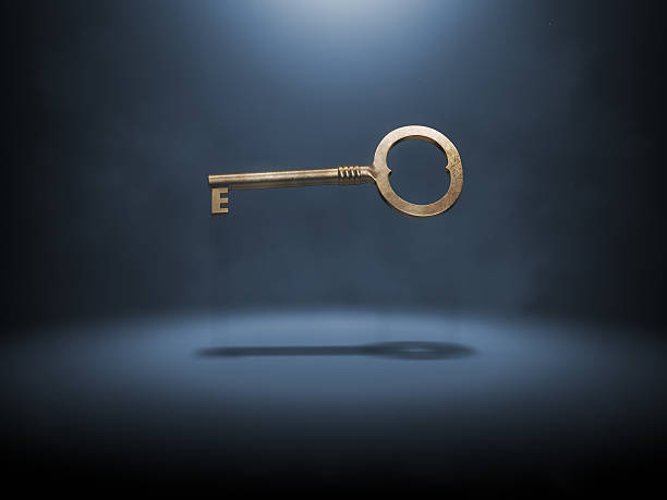 A singular gold key suspended in the air Old fashioned bronze key levitating over dark backgorund. Solution concept. antique key stock pictures, royalty-free photos & images