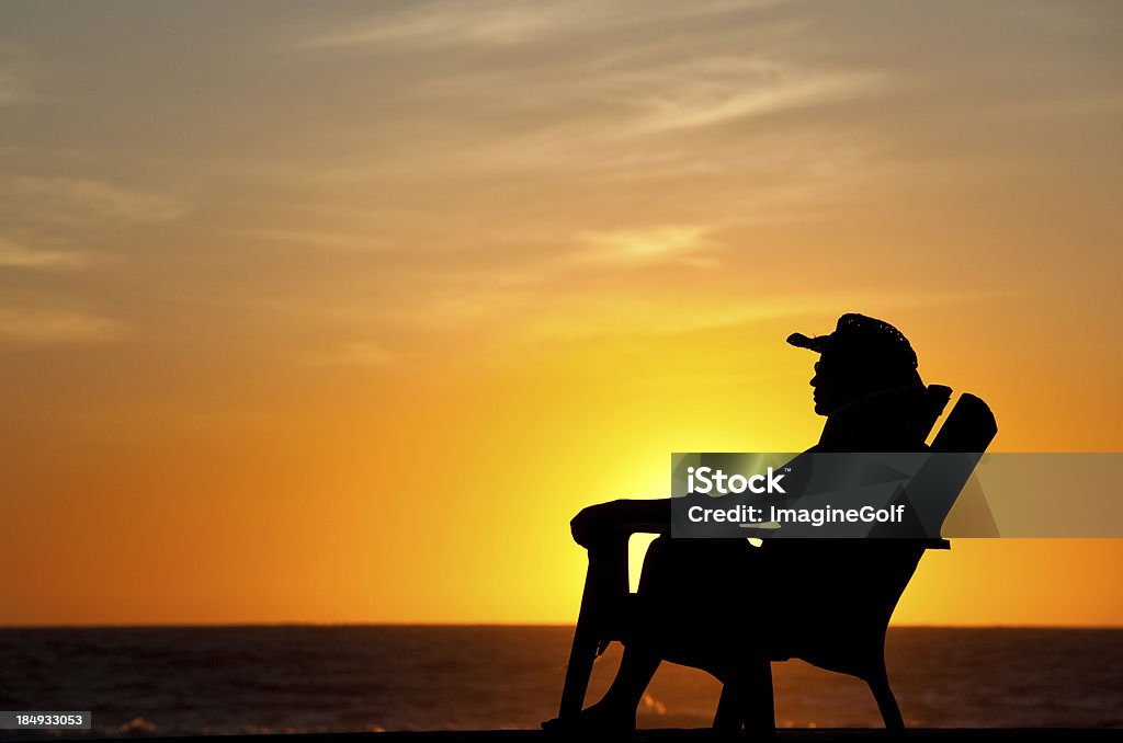 Woman Enjoying Tropical Sunset A woman enjoying a tropical sunset on the beach. Horizontal colour image. Adirondack chair. Pacific ocean. Summer resort. Reclining Stock Photo