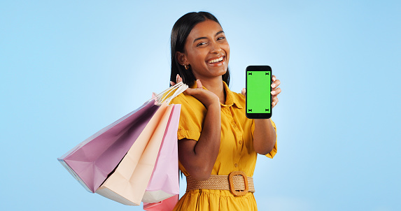 Smartphone green screen, shopping bag and portrait of happy woman show online shop, retail market or studio omnichannel. Tracking markers, phone chroma key or mockup space customer on blue background