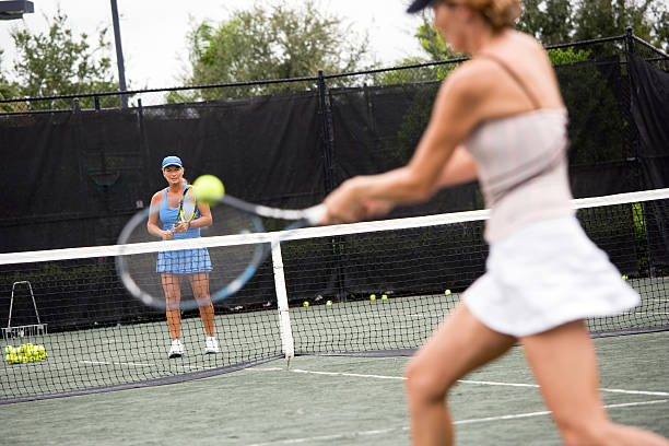 Tennis lesson Female tennis coach teaching backhand to student. tennis coach stock pictures, royalty-free photos & images