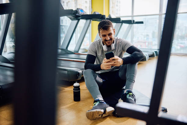 istock Happy athlete using cell phone while taking a break from exercising in a gym. 1849333789