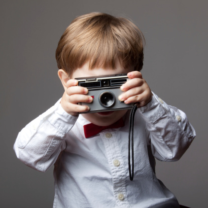 Little boy with shirt and bow tie holding old fashioned camera