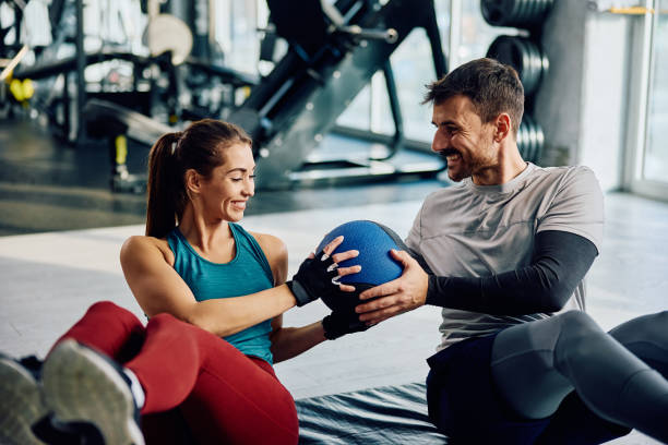 istock Happy athletic couple passing medicine ball while doing sit-ups in a gym. 1849346780