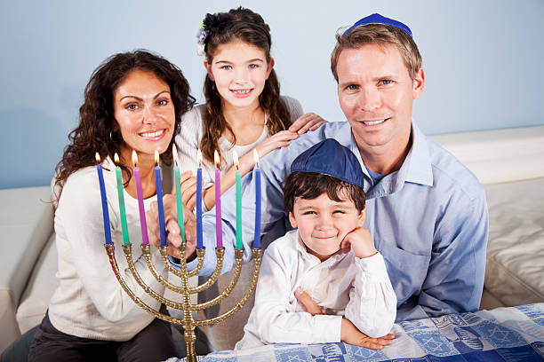 Hanukkah family portrait Portrait of family celebrating Hanukkah, lighting Menorah.  Focus on little boy (3 years) and father. judaism photos stock pictures, royalty-free photos & images