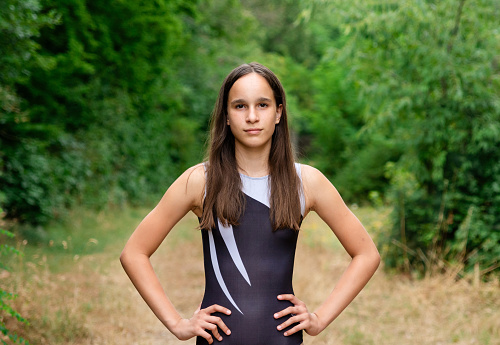 Portrait of happy teenage girl in sports clothing looking at camera in the nature
