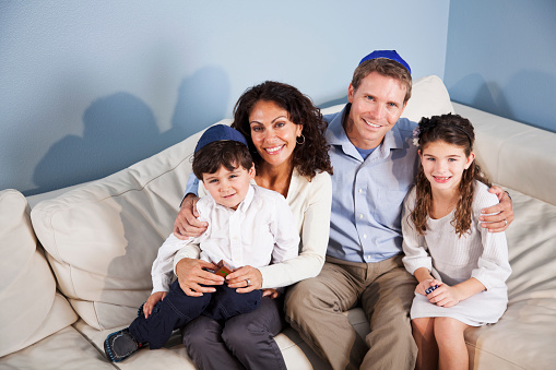 Portrait of family Jewish with two children, 3 and 9 years, sitting on couch.