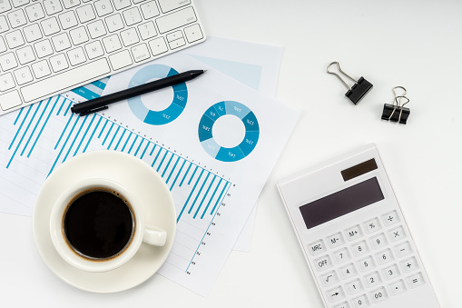 Top view photo of glasses cup of frothy coffee binder clips pen and calculator on notebooks on isolated light blue background with copyspace