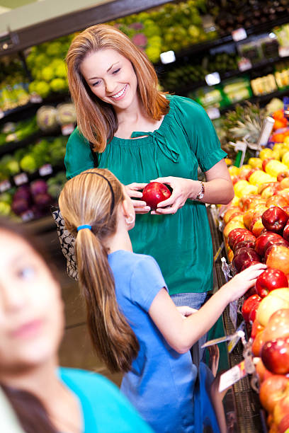 istock Mother and daughter at the grocery store selecting apples 184936765