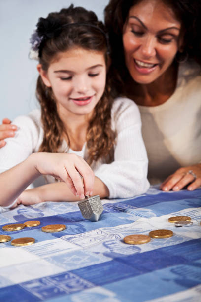 istock Mother and daughter spinning dreidl 184938297