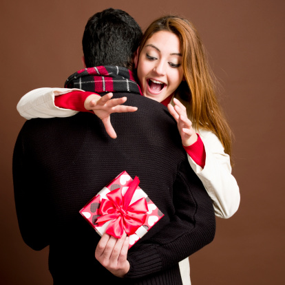 Young man hiding gift box from his girlfriend
