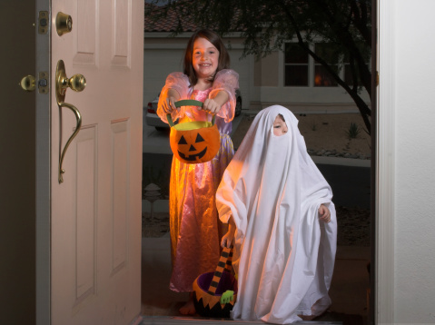 A couple of cute kids out looking for candy on Halloween.