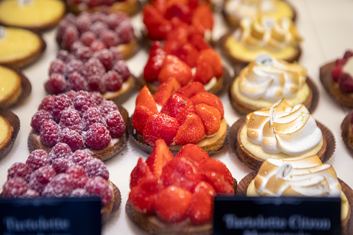 A selection of cream cakes and sweet pastries on display in the window of a patisserie in Paris