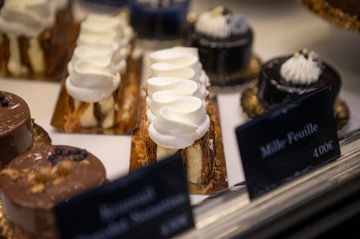 A selection of cream cakes and sweet pastries on display in the window of a patisserie in Paris