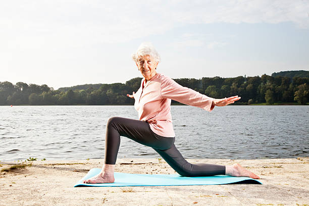 старший женщина, растяжения упражнения на озеро - aging process morning outdoors horizontal стоковые фото и изображения