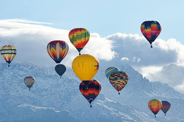 Hot Air Balloons with Sandia Mountains "Hot air balloons in the sky with the Sandia Mountains covered in snow and clouds in the background near Albuquerque, New Mexico" bernalillo county stock pictures, royalty-free photos & images