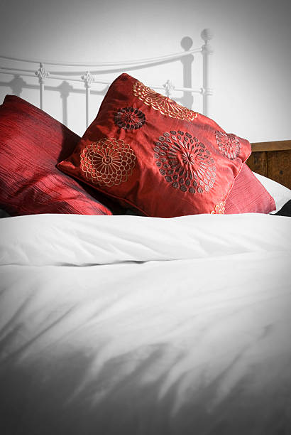 istock Metal bedstead bed with white duvet and red cushions 184938973