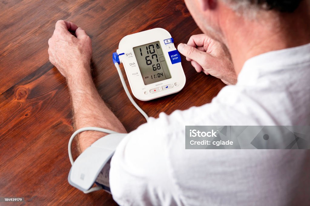 Mature adult man checking blood pressure Senior man monitoring his blood pressure at home Blood Pressure Gauge Stock Photo