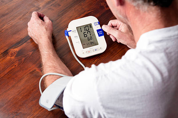 Mature adult man checking blood pressure Senior man monitoring his blood pressure at home monitoring equipment stock pictures, royalty-free photos & images