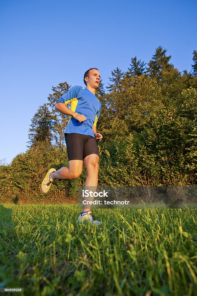 Jogging action Bottom view of young male athlete running on the meadow 20-24 Years Stock Photo