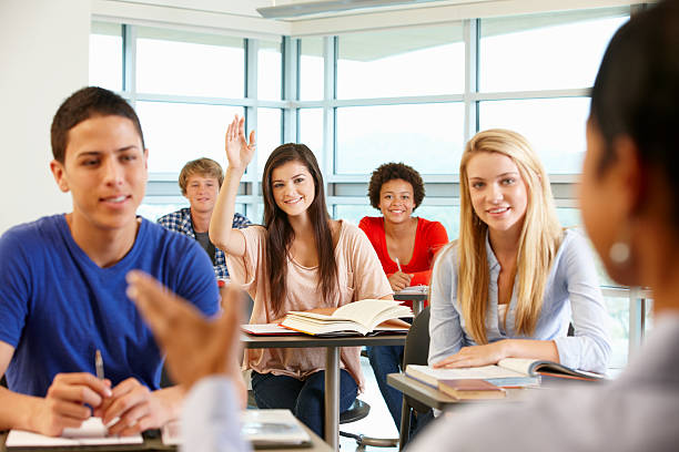 istock Multi racial teenage pupils in class one with hand up 184939781