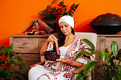 Beautiful young woman in white turban holds singing bowl and smiles. Soundhealing concept.