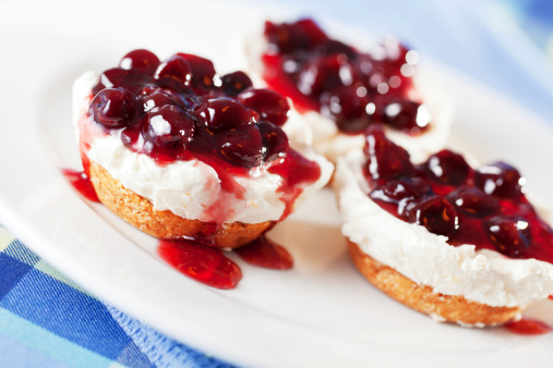 Three mini cheese cakes with cranberres served in a plate, close up