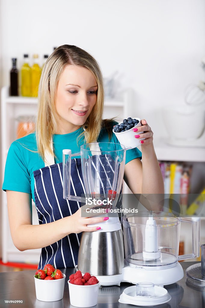 Adulto joven el vertido arándanos en un procesador de alimentos - Foto de stock de 18-19 años libre de derechos