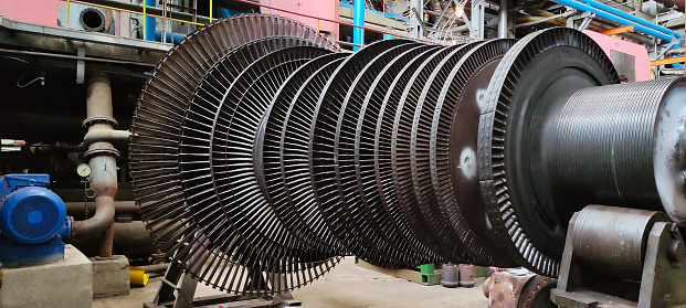 Disassembled steam turbine in the process of repairing and electric generator at a power plant