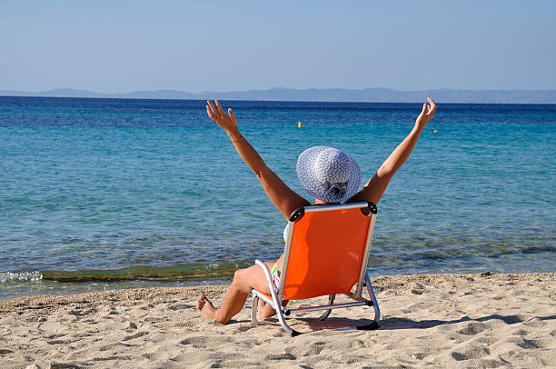 istock Woman enjoying sun on the beach with spread hands 184942167