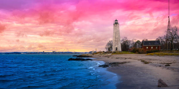 1847年にコネチカット州に建てられたモーガンポイントパークの海辺にあるニューヘイブンランドマーク灯台。アメリカの劇的な曇りの夕暮れ時のニューイングランドの冬の海岸風景。 - connecticut lighthouse new haven coastline ストックフォトと画像