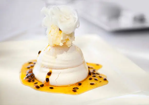 Pavlova meringue desert with passionfruit sugar syrup & ice cream topped off with fairy floss