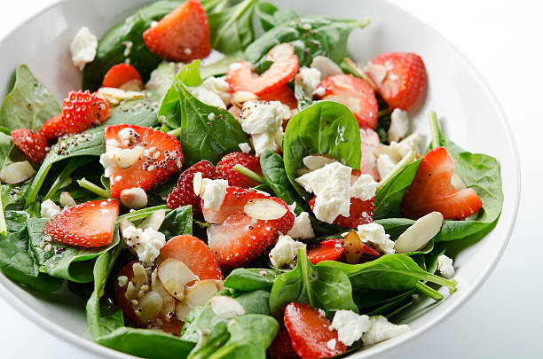 Green salad with strawberries and spinach SEVERAL MORE IN THIS SERIES. Fresh salad of baby spinach leaves, sliced strawberries, slivered almonds, feta cheese, and a light dressing. Shallow DOF. spinach stock pictures, royalty-free photos & images